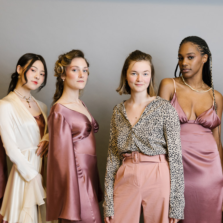 A student and models wearing pink and cream clothing she designed. 