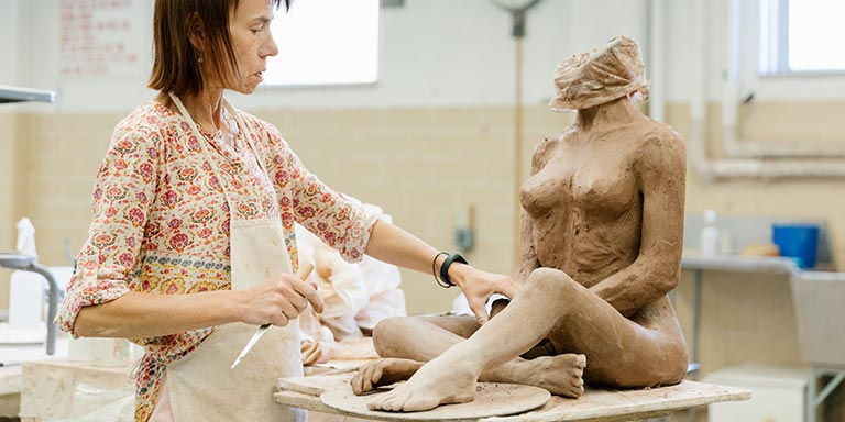 A person works on a sculpture of a woman's body.