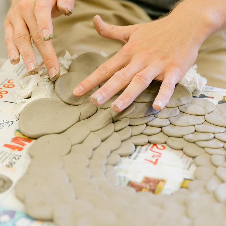 A person works with circles of clay.