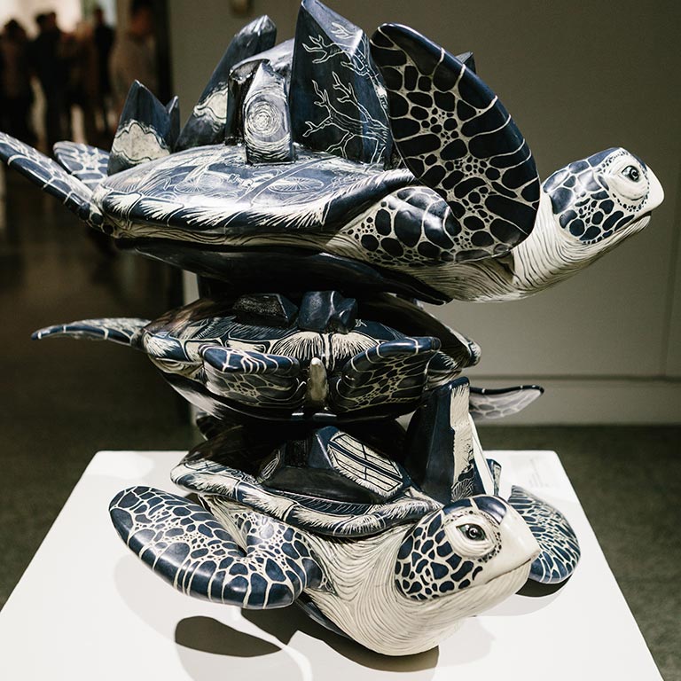 A sculpted piece of three turtles on top of each other.