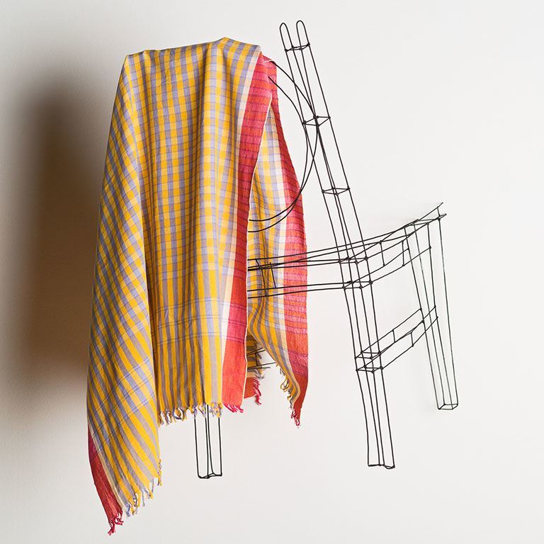 A plaid fabric hangs on a chair.