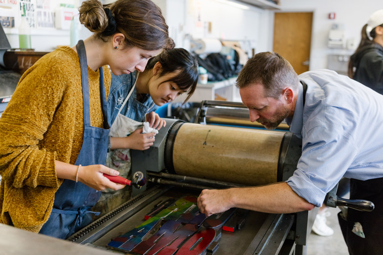 A professor and students work at a letterpress.