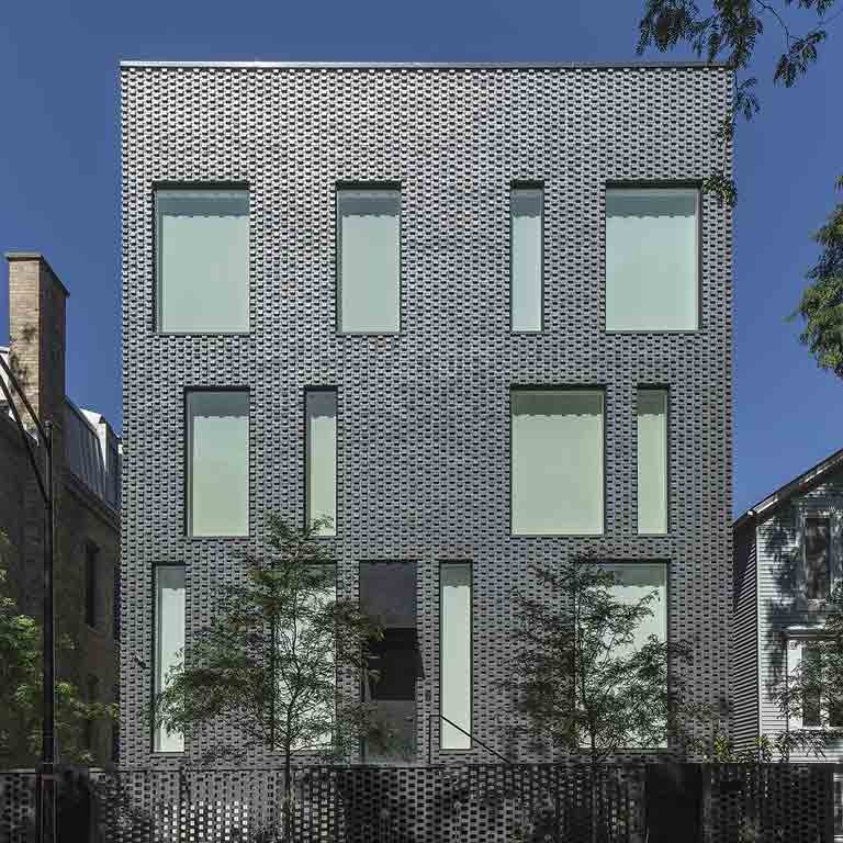 A photo of a silver building with multiple sized and shaped rectangular windows. 