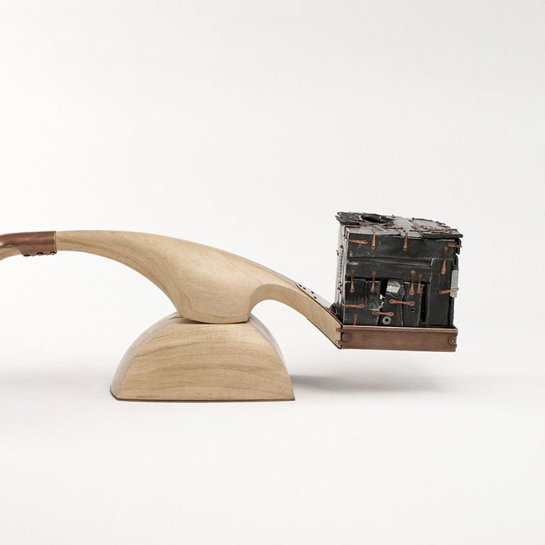 A wooden scale with a metal sculpture on one end.