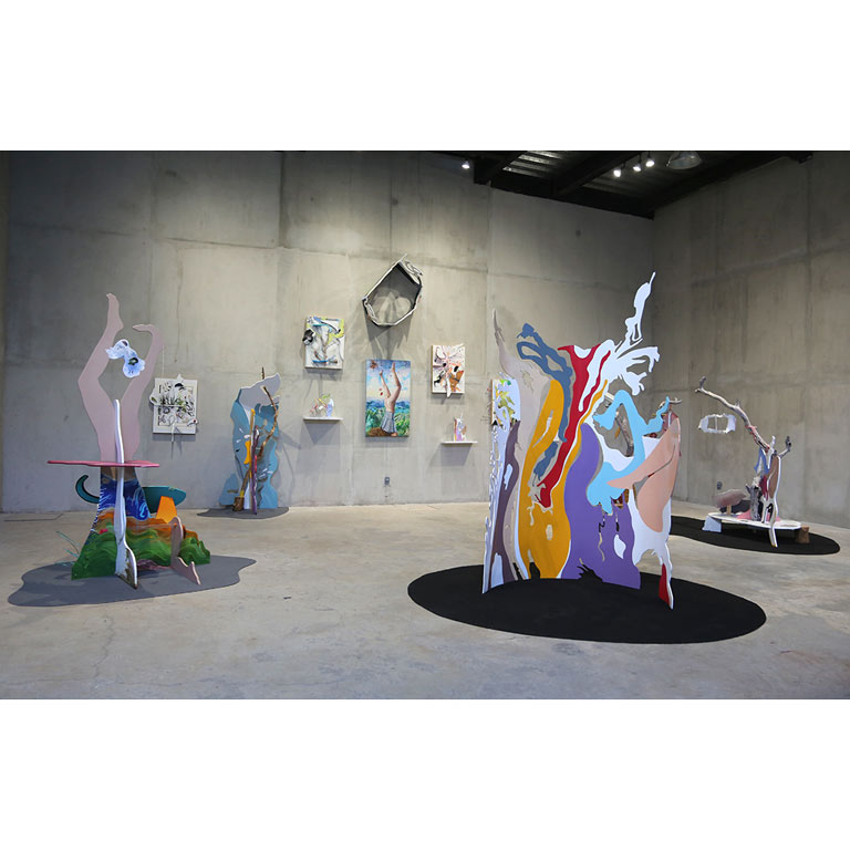 Multiple colorful sculptures in a cement art gallery