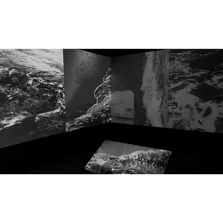 Ocean waves projected on multiple screens in black and white