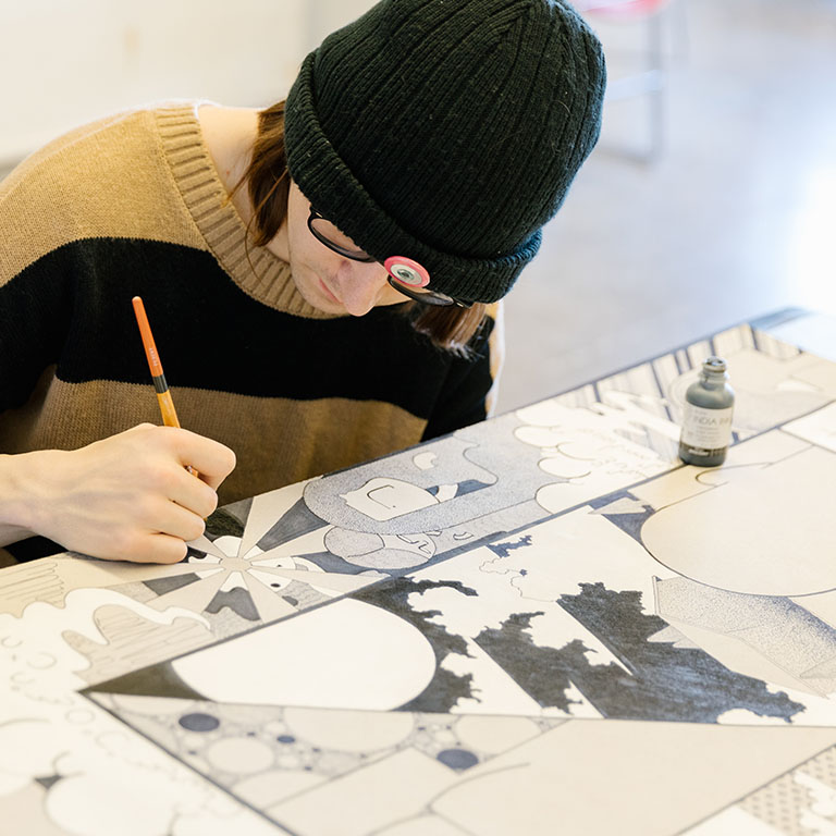 A person draws with a pencil at a table.