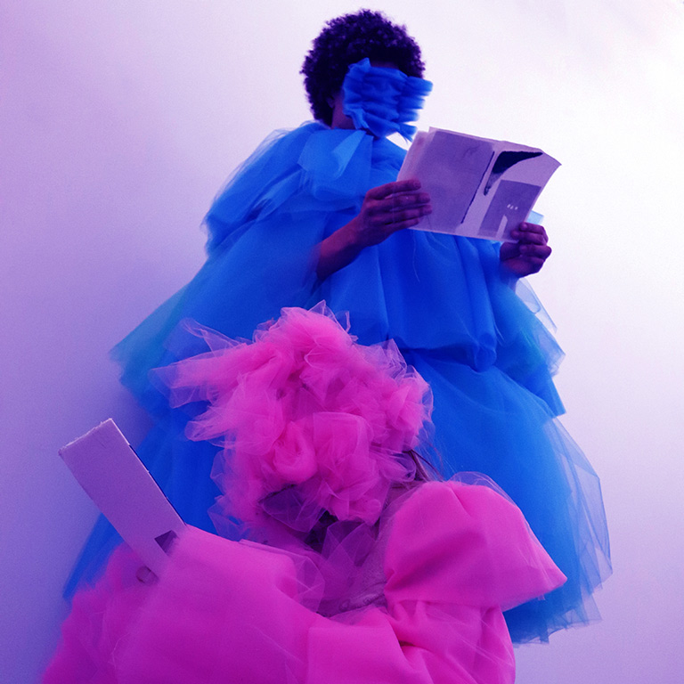 A photo of two figures dressed in purple and pink tulle. 