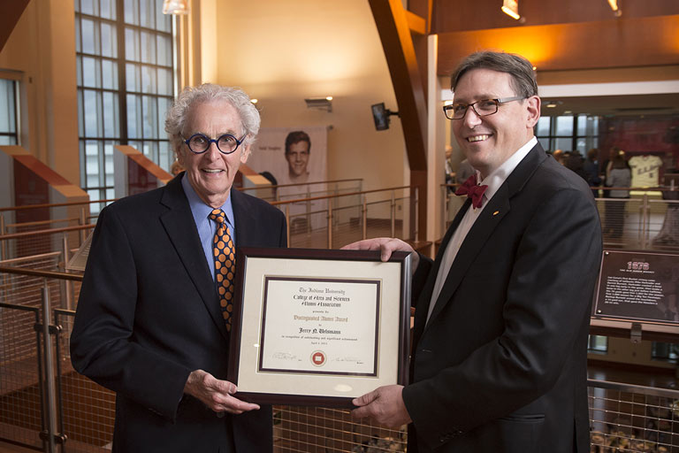 A photo op of a person giving another person a framed award. 