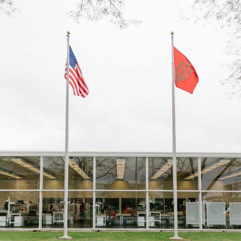 Two flags in front of a glass building