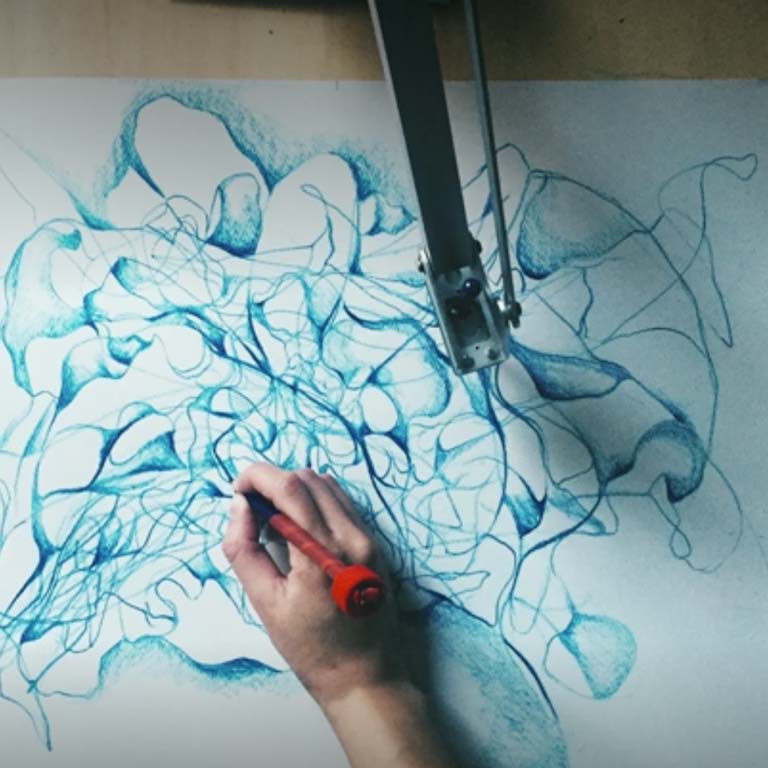 An image of a person drawing with the help of a robotic arm