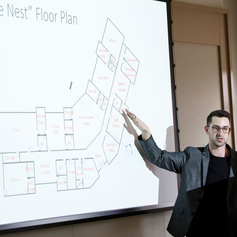 A person points to a floor plan on a wall